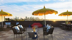 A rooftop patio with outdoor seating, umbrellas, and a city skyline view. - The Carter by Avantstay 3rd Floor, 15 Bedrooms (Nashville)