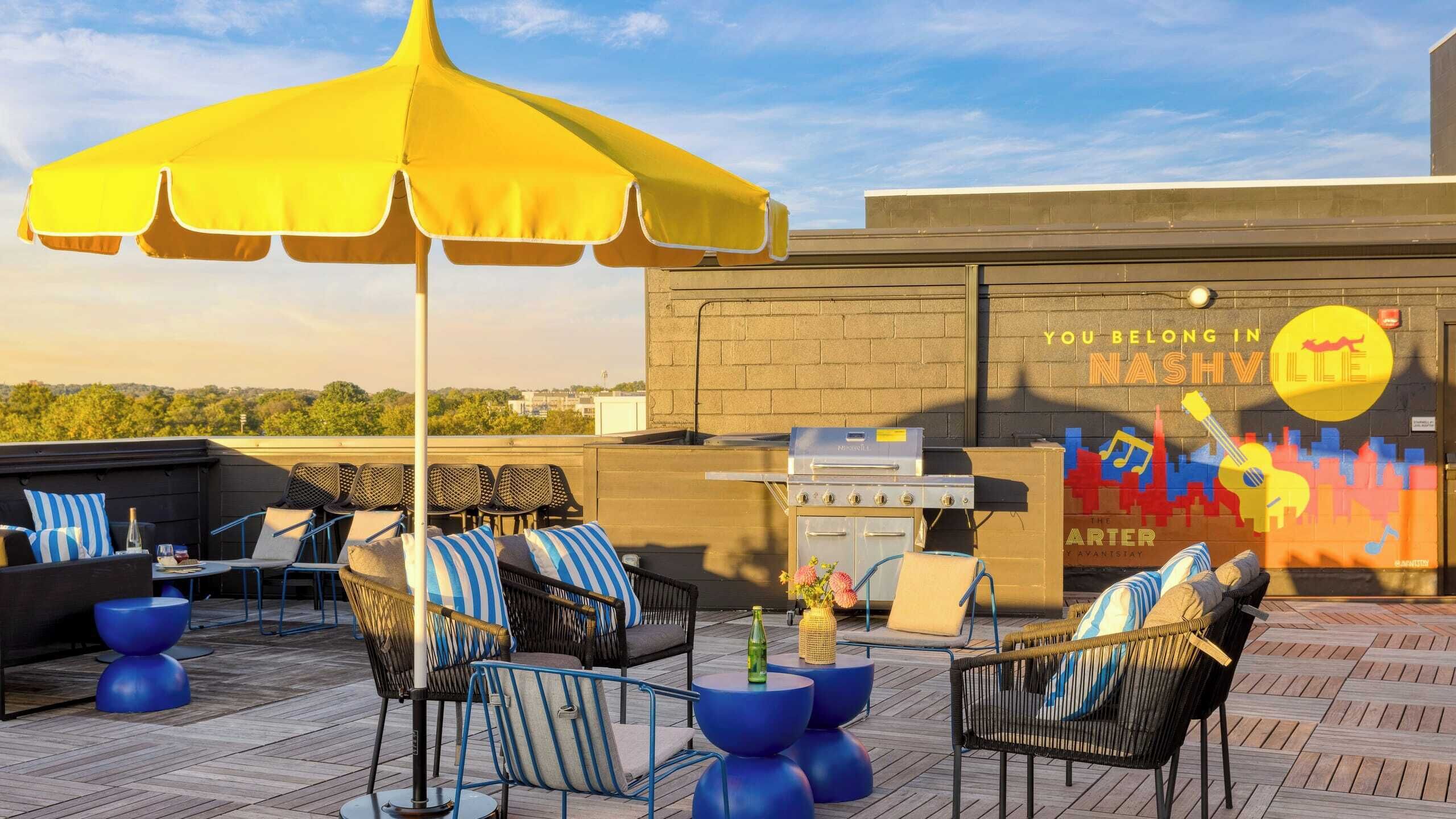 A rooftop patio with outdoor seating, a grill, and a mural.