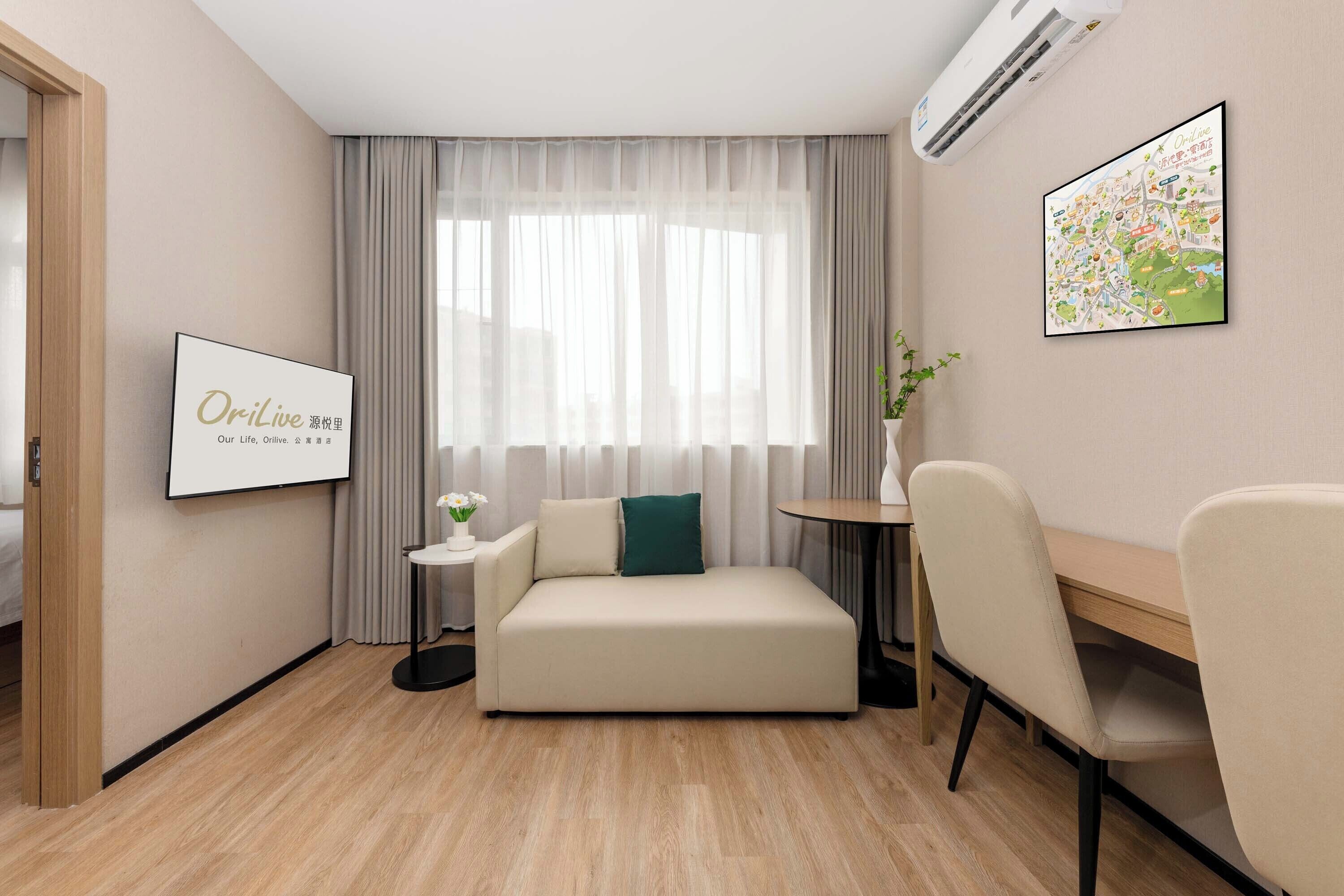A modern hotel room with a sofa, a small table, a chair, a framed picture, and a map on the wall.