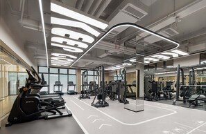 A modern gym with treadmills, weight machines, and mirrors. - Dongguan Guomao Yuanyue Li Youth Hotel (Dongguan)