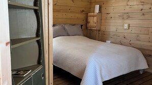 Een houten kamer met een bed, een klein kastje en een plank.
