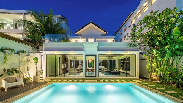 Une maison moderne dotée d’une piscine, de portes vitrées donnant sur un espace de vie et d’une végétation luxuriante.