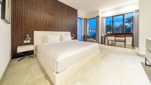 Une chambre moderne avec un grand lit, un bureau et une vue sur l’extérieur.
