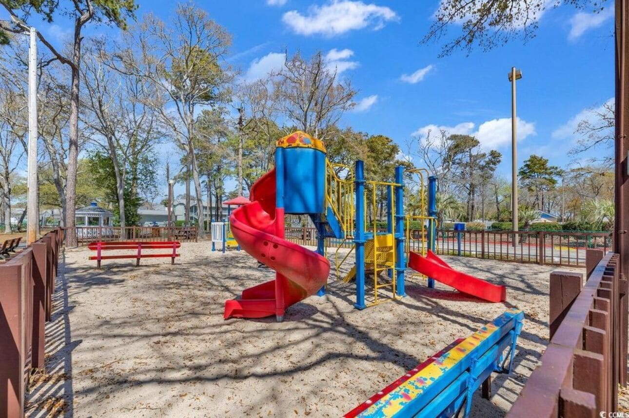 A playground with a red spiral slide and yellow and blue play structures.