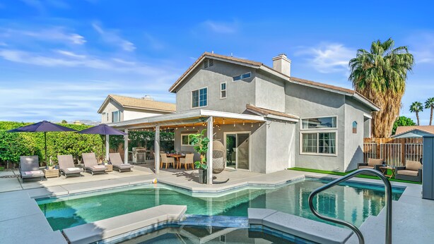 A modern house with a swimming pool, outdoor seating, and a covered patio.