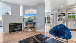 A modern living room with a fireplace, a television, and a blue chair.