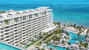 Un hôtel de grande hauteur doté de nombreux balcons donnant sur une piscine et l’océan.
