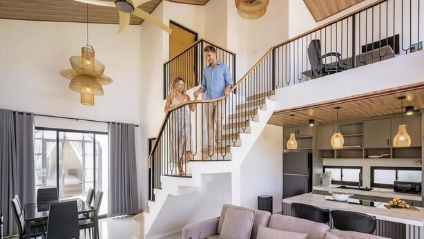 Un vaste espace de vie comprenant un canapé, une table à manger et un escalier.