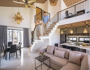 A spacious living area with a sofa, dining table, and staircase. - Algera Villa Ubud (Mas)