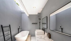Um banheiro moderno com uma banheira independente, um espelho grande e design minimalista.