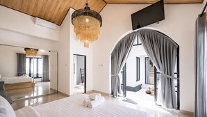 Une chambre à coucher moderne avec un grand lit, un lustre, une télévision et une vue sur l’extérieur.