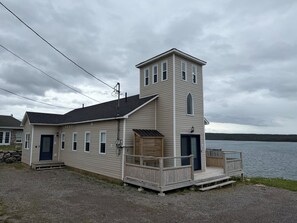 Un bâtiment à deux étages avec une jetée qui s’avance dans un lac, agrémenté d’une petite tour et d’un porche couvert.