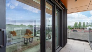 A balcony with a glass door, a sofa, and a small table. - Manchester Square Urban Stay – Easy To Everything (Christchurch)