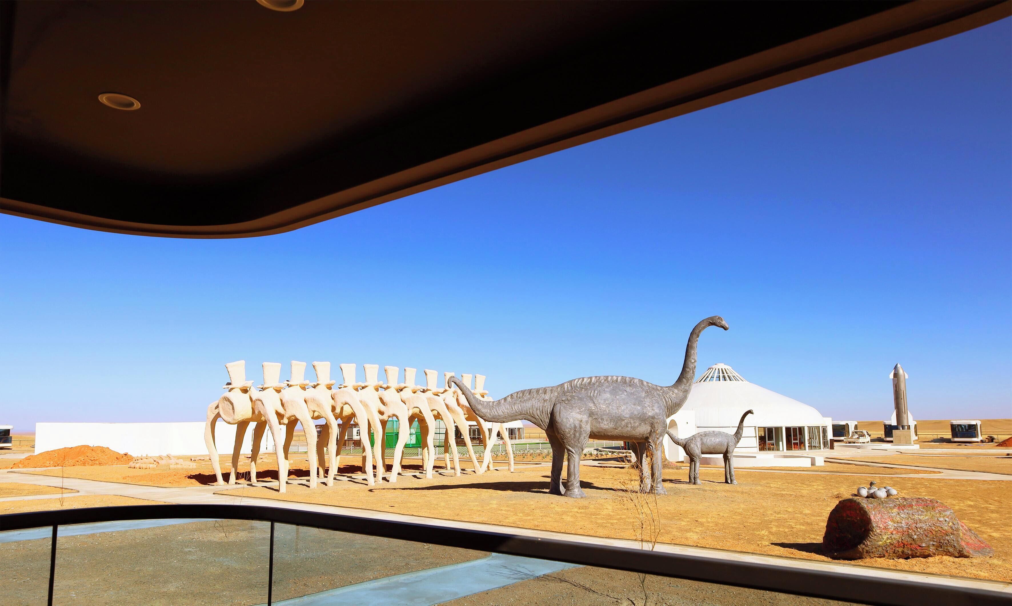 Eine Dinosaurierausstellung mit einem großen Sauropoden und einer Reihe kleinerer Dinosaurier.