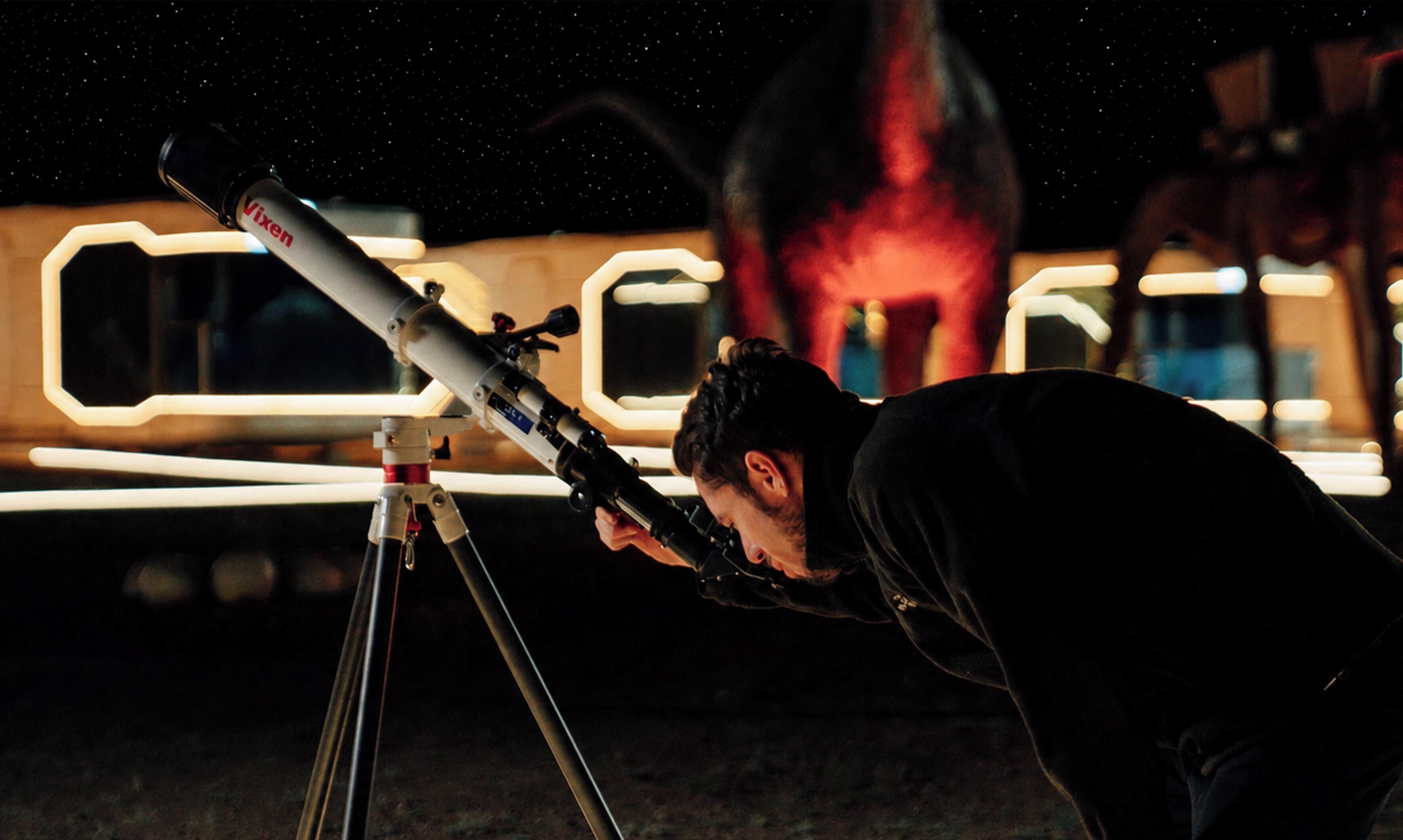 A person using a telescope with a tripod.