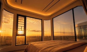 A bedroom with a large bed, multiple windows, and a view of the sunset. - Tegri Gobi Resort (Bulgan)