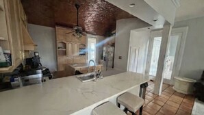 A spacious kitchen with a large island, wooden cabinets, and a ceiling fan. - Spacious charming lake house on Lake Hartwell (Toccoa)