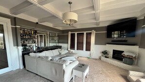 A modern living room with a large sectional sofa, a small coffee table, and a television mounted on the wall. - Spacious charming lake house on Lake Hartwell (Toccoa)