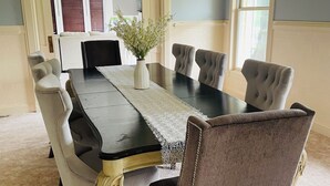 A dining room with a black table, beige upholstered chairs, and a chandelier. - Spacious charming lake house on Lake Hartwell (Toccoa)