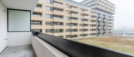Ein Balkon mit Blick auf ein mehrstöckiges Gebäude, das Balkone und eine Glasfassade zeigt.