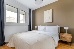 A bedroom with a large bed, a nightstand with a lamp, a window with curtains, and a wall-mounted abstract art piece. - Blueground | Favoriten, jacuzzi, nr Belvedere (Vienna)