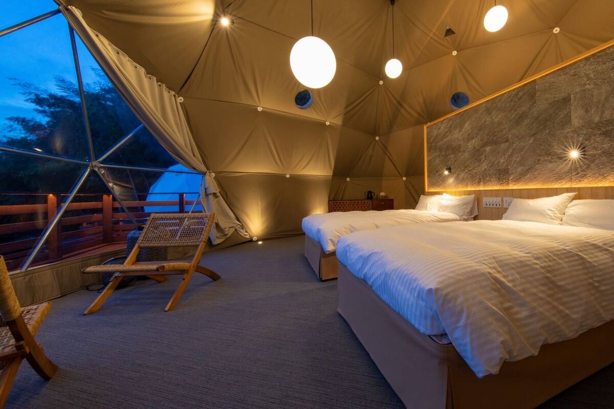 Een tentverblijf met een bed, een stoel en uitzicht door een raam.