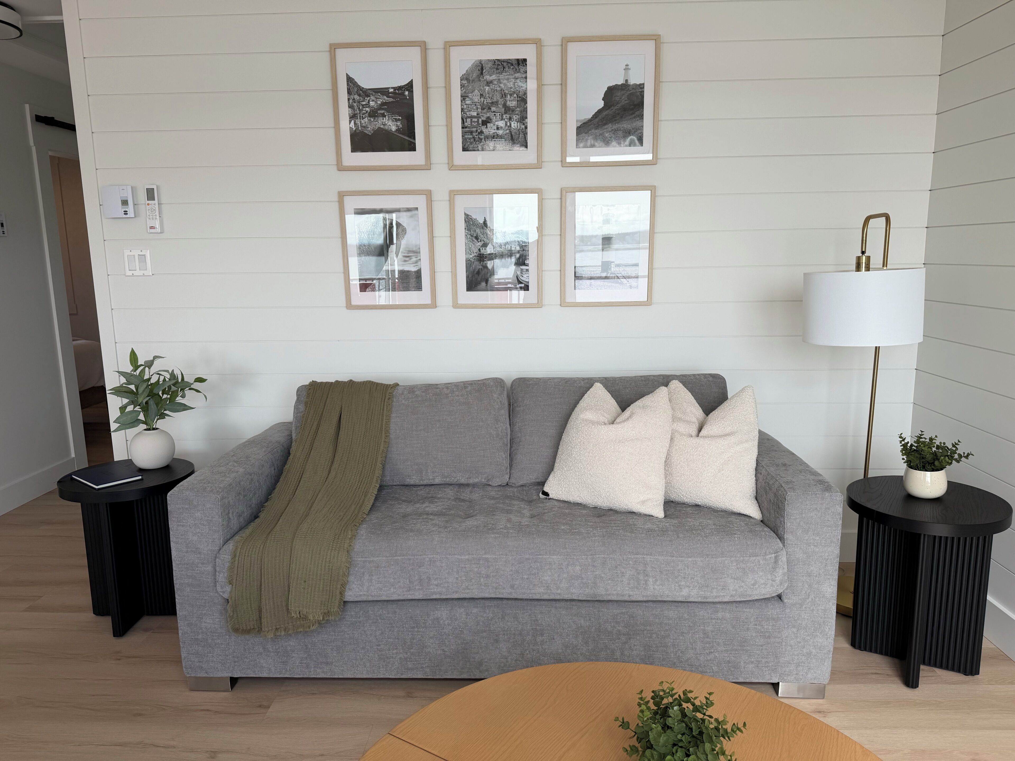 Ein modernes Wohnzimmer mit einem grauen Sofa, einer Decke und einer Lampe.