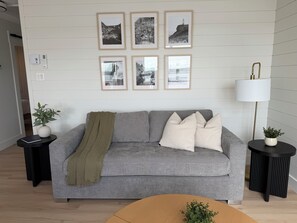 Un salon moderne avec un canapé gris, un plaid et une lampe.