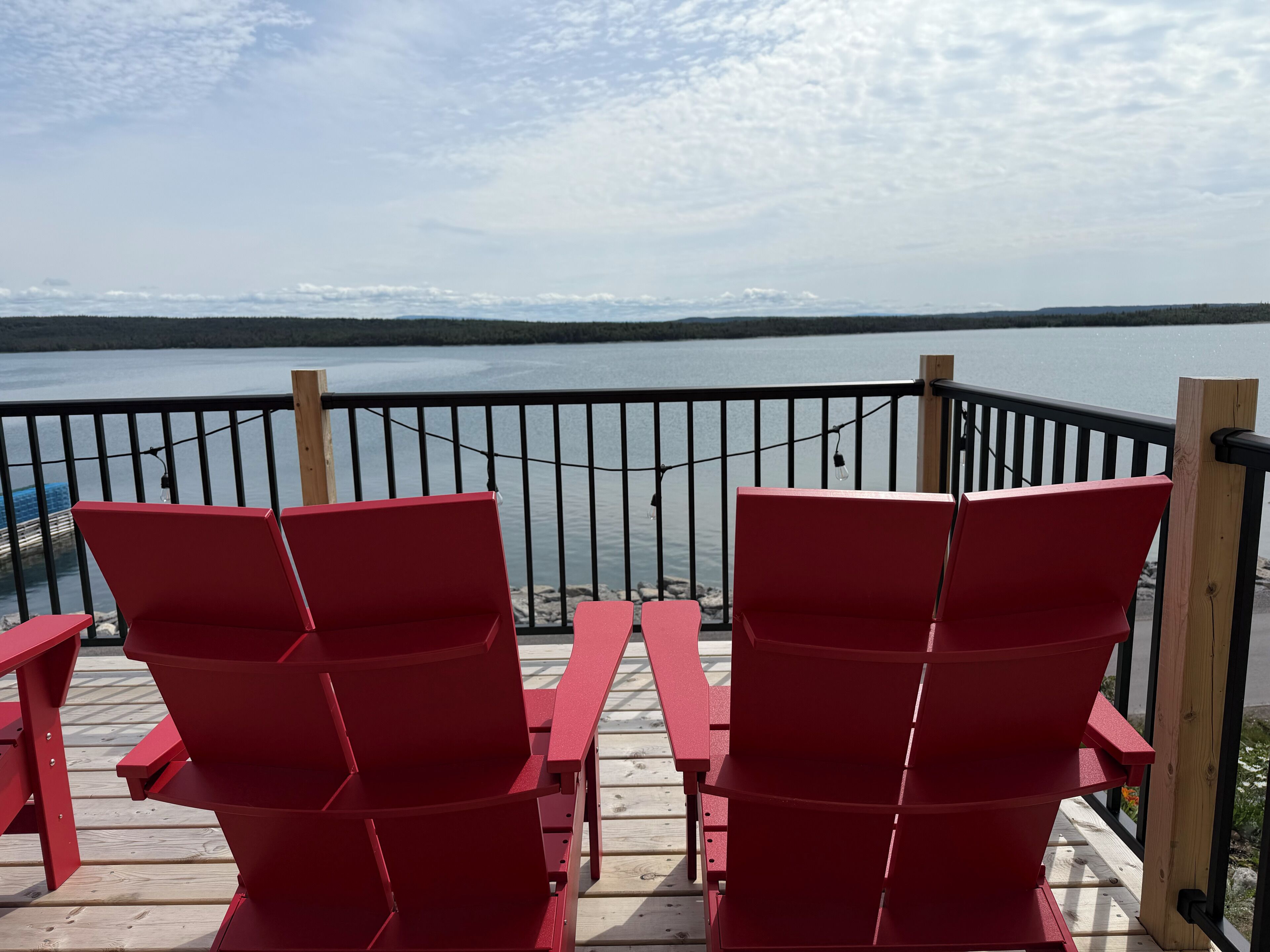 A deck with red chairs overlooking a body of water.