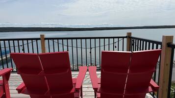 A deck with red chairs overlooking a body of water.