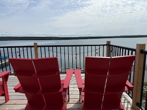 Une terrasse avec des chaises rouges donnant sur une étendue d’eau.