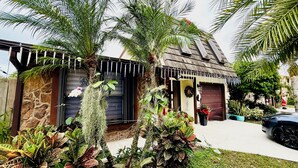 Ein Haus mit Steinwänden, einer Holztür zur Garage und einer Veranda mit einem Blumentopf.