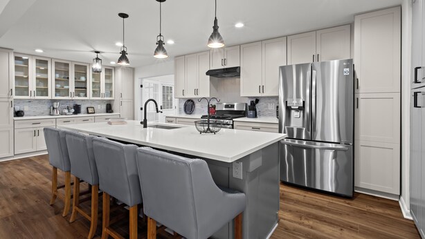A modern kitchen with white cabinets, stainless steel appliances, and a central island with bar stools. - Chic & Comfy Stay • Close to Everything (Marietta)