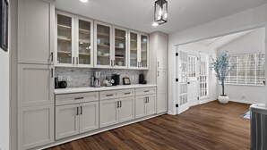 A modern kitchen with white cabinets, a marble backsplash, and a wooden floor. - Chic & Comfy Stay • Close to Everything (Marietta)