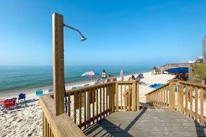 A wooden deck with a metal railing overlooking a beach with umbrellas and beach chairs. - Beachfront Getaway | Sunroom with Gulf Views, Pool & Spacious 3BR Layout | BEACHBALL PROPERTIES (Gulf Shores)