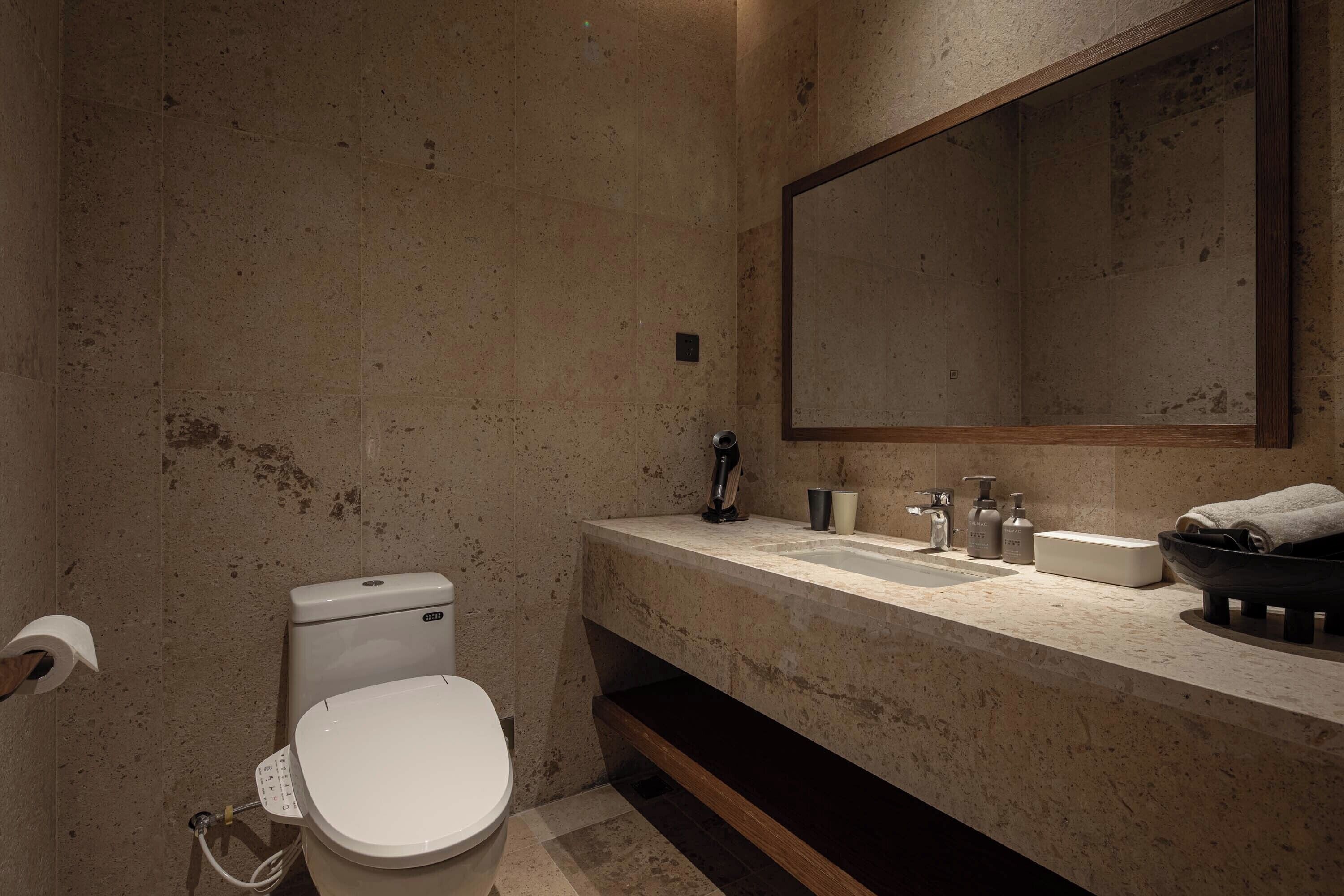 Un baño moderno con inodoro, lavabo y espejo.