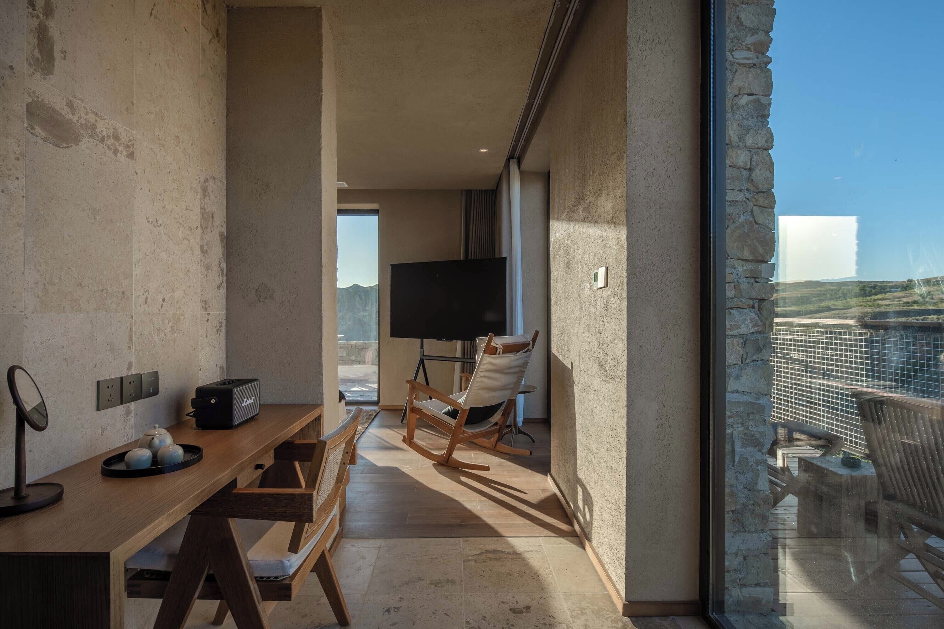 Una sala moderna con una mesa de madera, un televisor y un sillón mecededor.