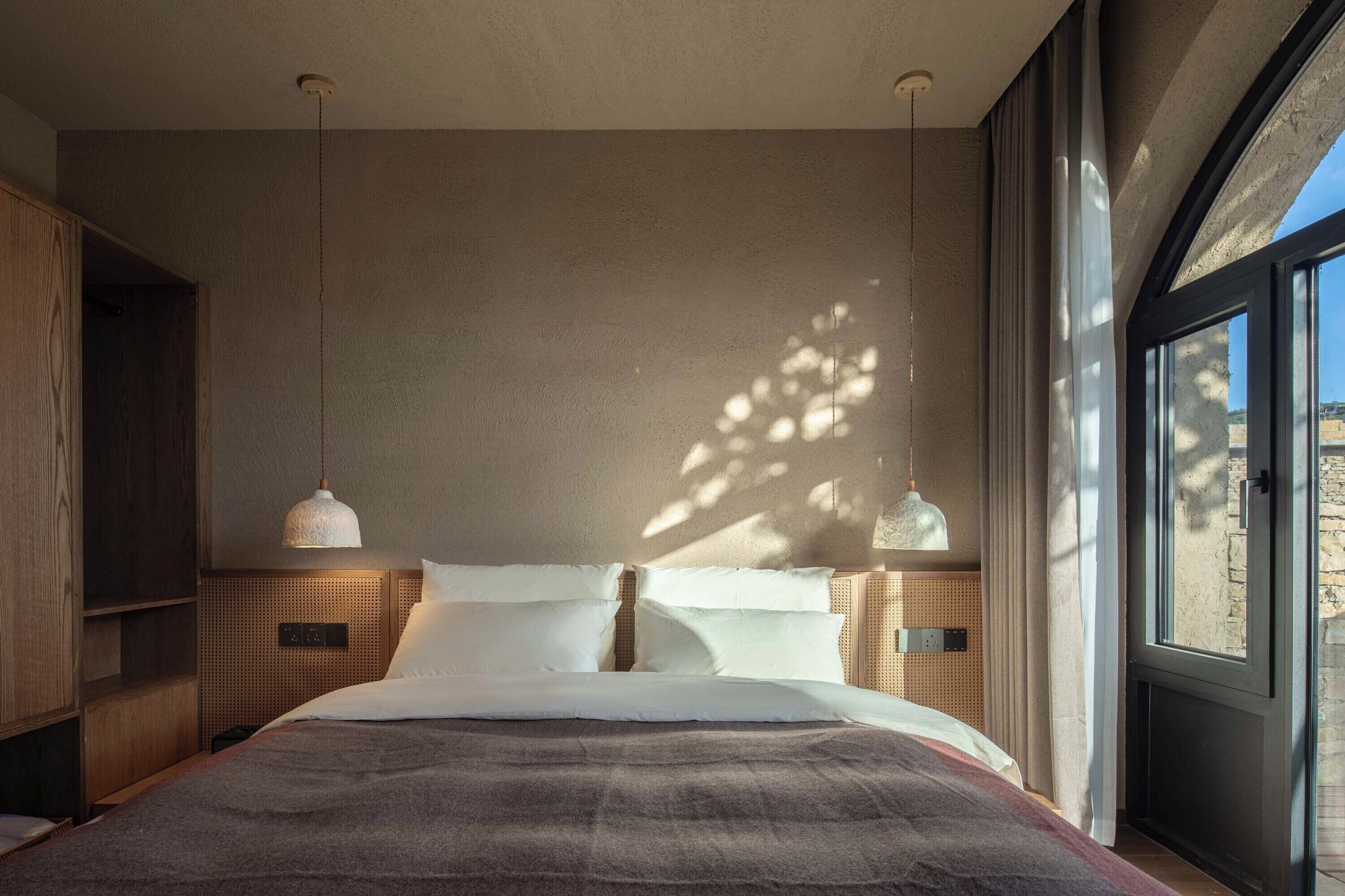 A modern bedroom with a large bed, two bedside tables, and a large window.