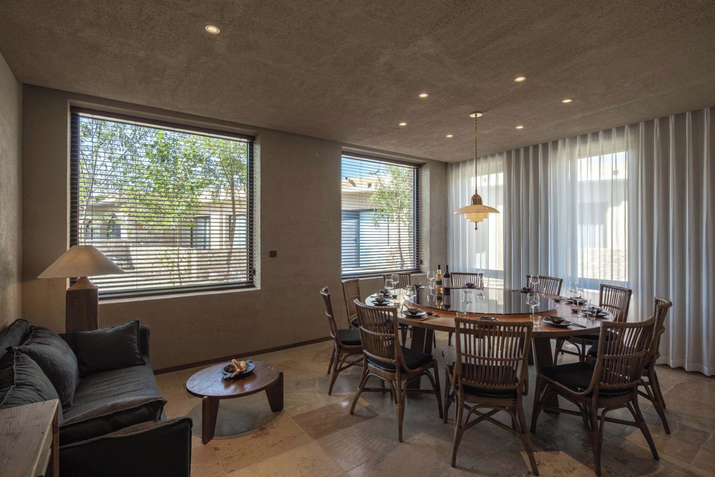 A dining area with a round table, wicker chairs, and a lamp.