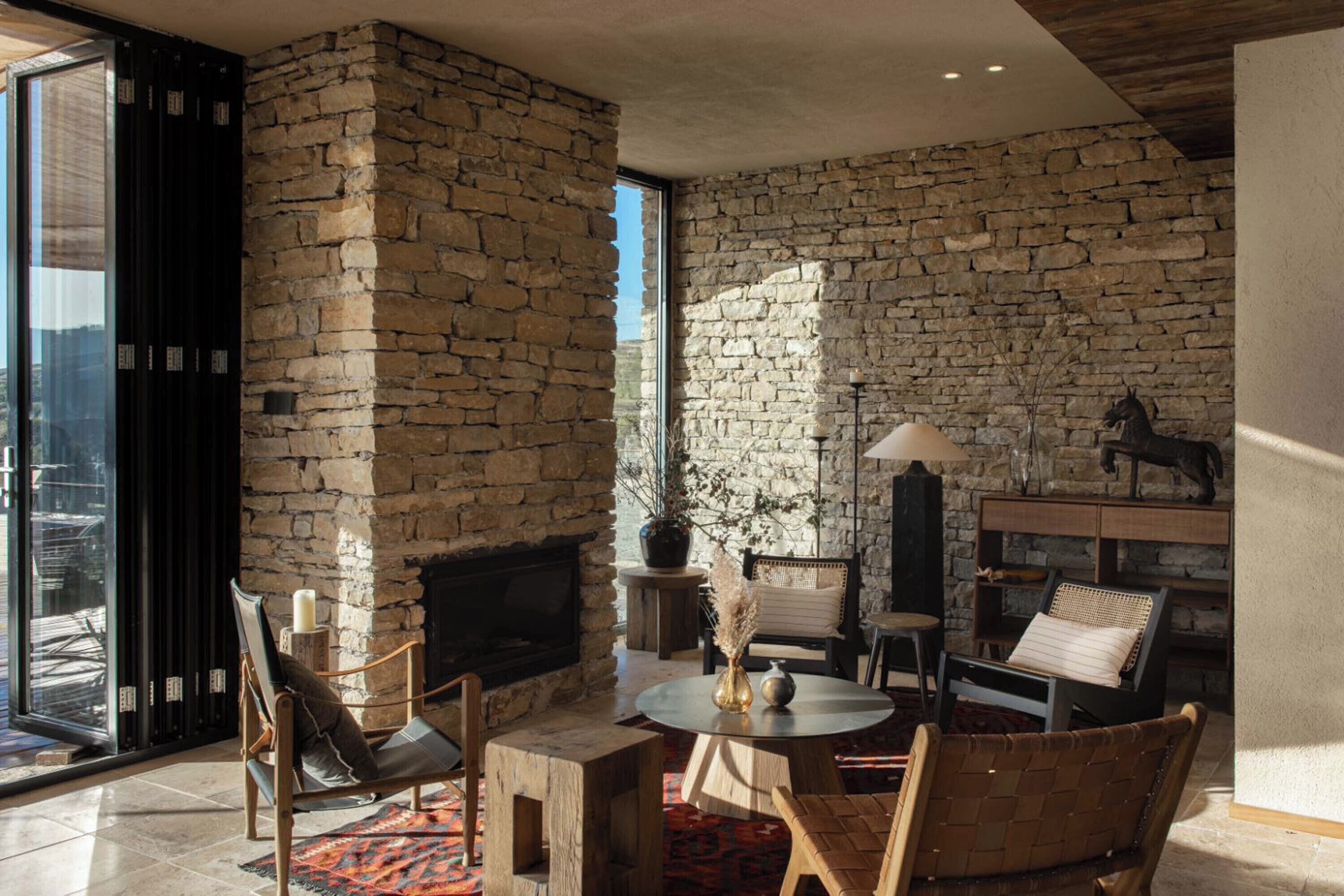 Una sala de estar acogedora con una pared de piedra, chimenea y asientos cómodos.