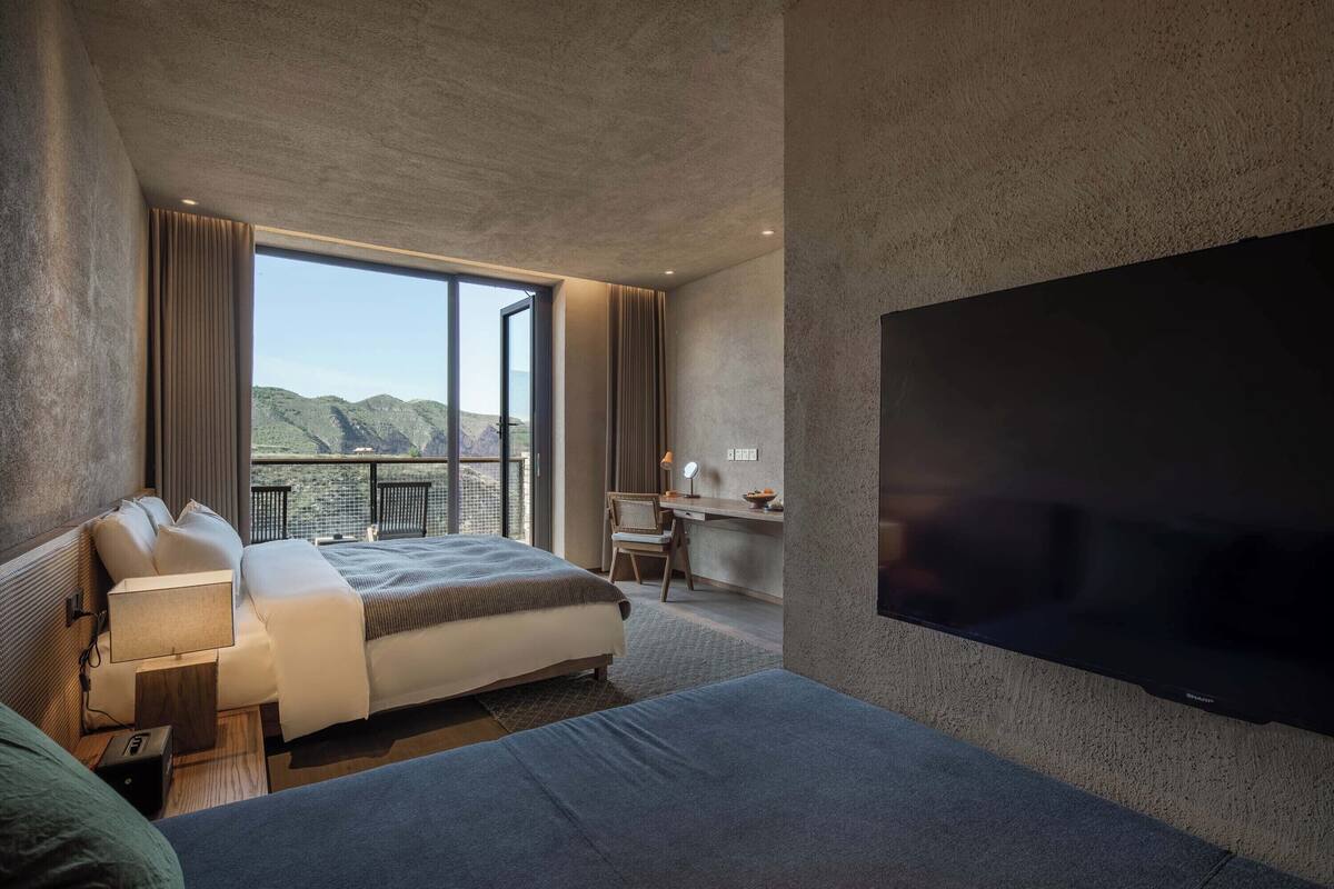 A modern hotel room with a large bed, a desk, and a TV.