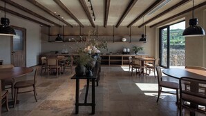 Cucina spaziosa con travi in legno, lampade a sospensione moderne e un'ampia finestra con vista sull'esterno.