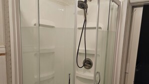 Une cabine de douche fermée par des parois en verre, équipée d’une barre d’appui et d’un pommeau de douche.