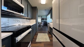 A modern kitchen with dark cabinetry, a marble backsplash, and a built-in oven. - Updated 3BR Home – Quiet, Comfortable Stay with Luxury Master & Spa Shower (Kennewick)
