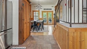 A kitchen with wooden cabinets, a stainless steel refrigerator, and a dining area with a table and chairs. - Close to Shows, Dining & Golf • 2BR + Loft Cabin (Branson)
