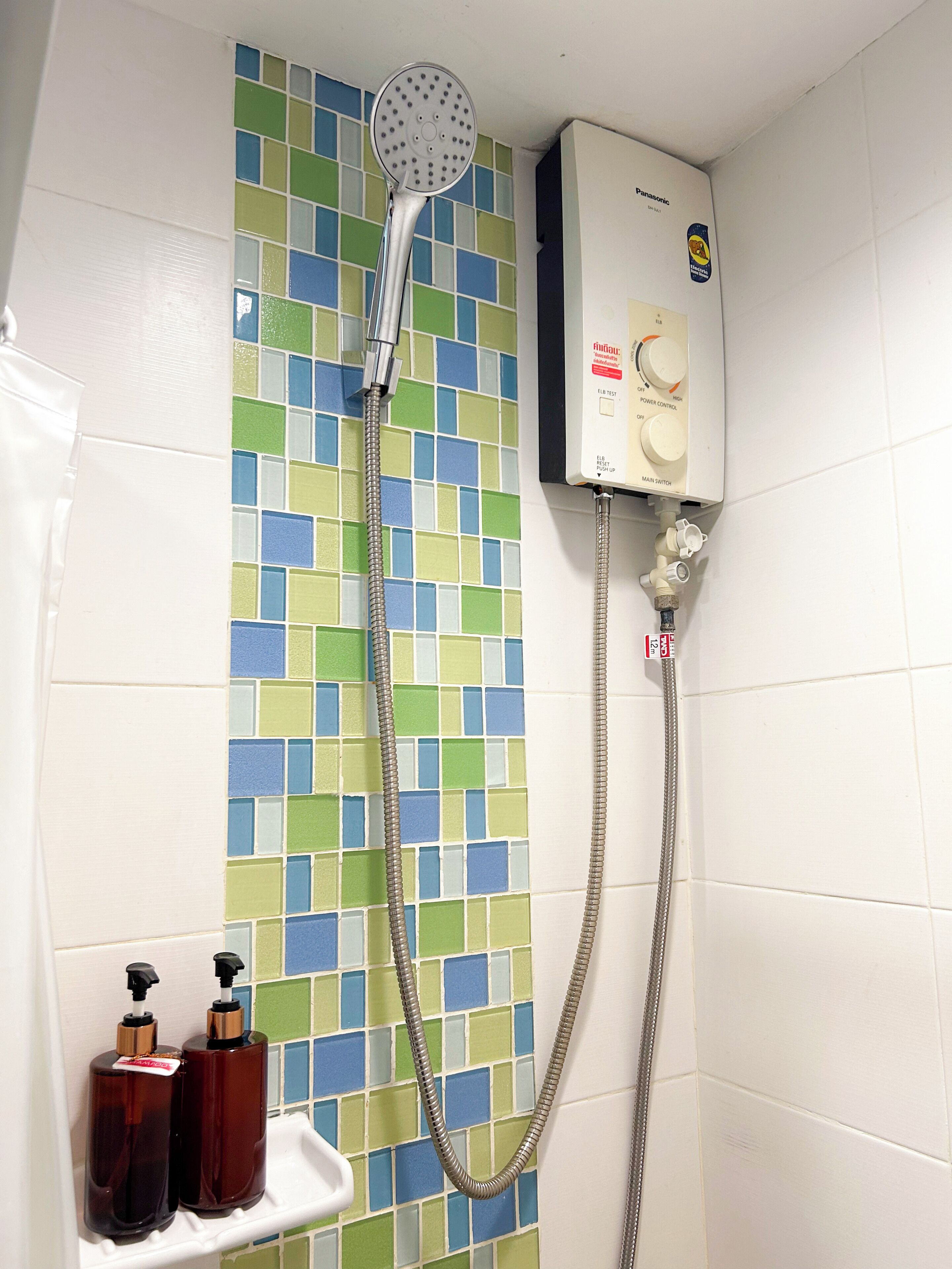 A bathroom with a shower, a tiled wall, and a water heater.