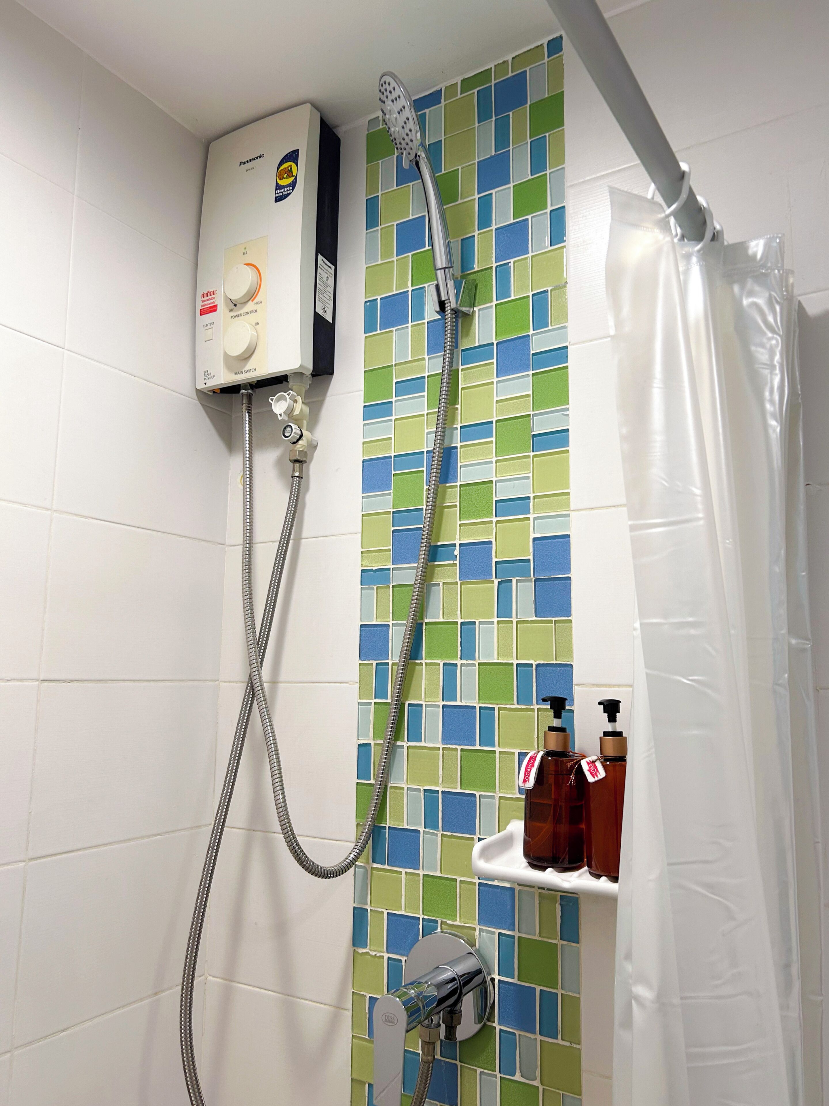 A bathroom with a shower, a Panasonic water heater, and a tiled wall.