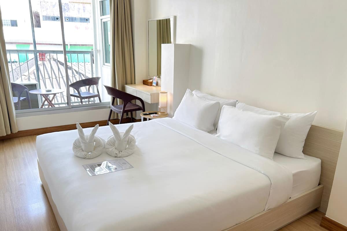 Une chambre d’hôtel avec un grand lit, un bureau, une chaise et une vue sur l’extérieur.