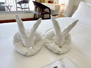 Une chambre d’hôtel avec un lit bien fait, une petite table avec une lampe et une chaise visible à travers la fenêtre.