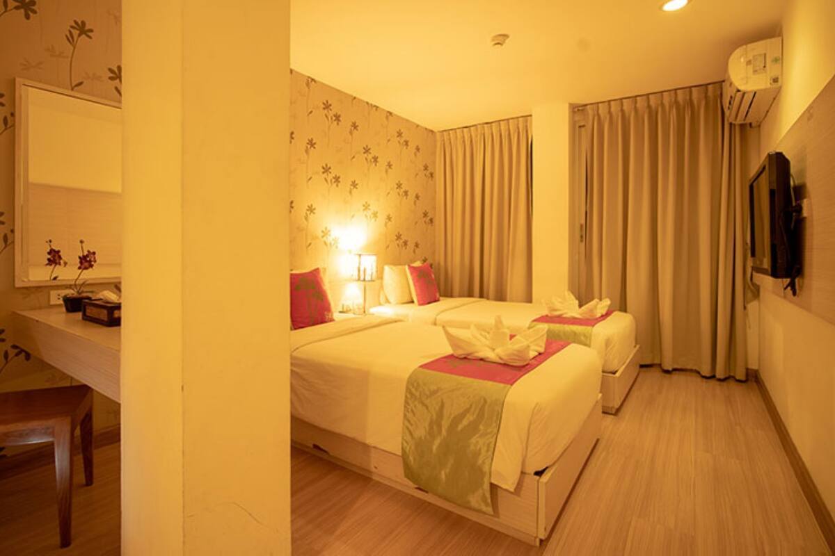 Une chambre d’hôtel avec deux lits, un bureau, une chaise et un téléviseur.
